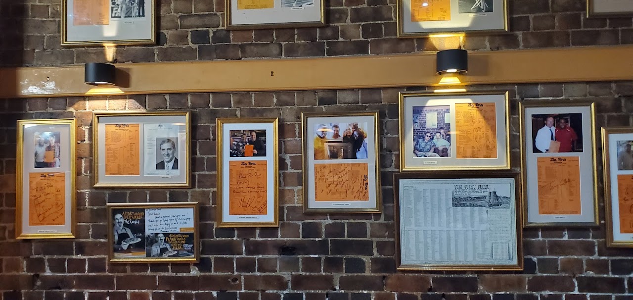 Framed memories and menus on the brick wall inside Zia Pina Pizzeria